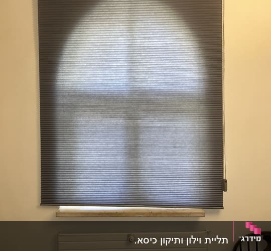 תריס גלילה אפור על חלון עם רדיאטור מתחת